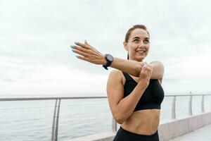 A woman running coach smiles and trains in the fresh air. Runner athlete in fitness clothes and running shoes. A strong person and sports for health. photo