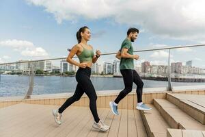 People in sportswear together runners, physical education and sports. Running man and woman train.  Using smart watches and a fitness app.  Team exercises of a young couple. photo