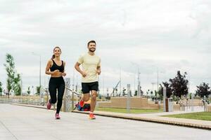 Sports people, training together, running full-length in the fresh air. A woman and a man doing fitness exercises for a healthy lifestyle. Friends run together. photo