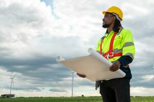 Smart engineer with protective helmet holding the blueprint working at electrical turbines field photo