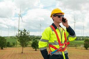 A smart engineer with protective helmet on head, using smartphone at electrical turbines field photo