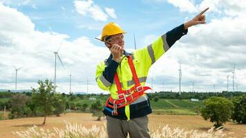 A smart engineer with protective helmet on head, using walkie talkie at electrical turbines field photo
