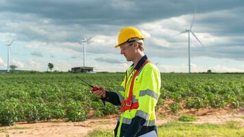 A smart engineer with protective helmet on head, using walkie talkie at electrical turbines field photo