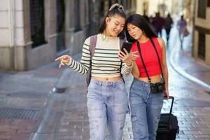 Asian girlfriends traveling together walking on street and browsing smartphone photo