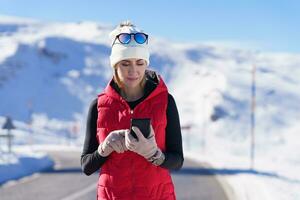 juguetón mujer utilizando teléfono en invierno campo foto