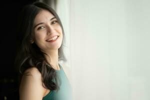 Portrait of a beautiful asian woman in green shirt standing near the window photo