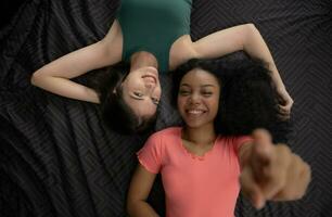 Top view of two young women lying on bed and smiling at each other photo