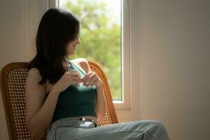 Beautiful asian woman sitting on chair and looking out the window photo