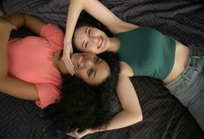 Top view of two young women lying on bed and smiling at each other photo