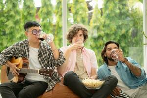 Multiethnic group of friends having fun playing guitar and singing together at home photo