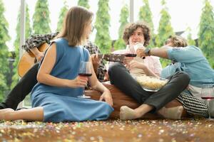 Multiethnic group of friends having fun playing guitar and singing together at home photo