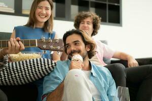 Multiethnic group of friends having fun playing guitar and singing together at home photo