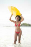 Surfer girl with her surfboard on the beach. photo