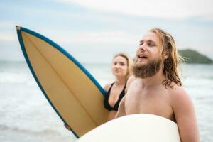Couple of surfers holding hands and looking at each other on beach photo