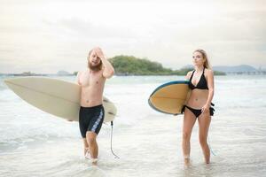 Young man and woman holding surfboards ready to walk into the sea to surf. photo