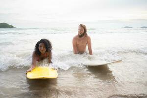 joven hombre y mujer teniendo divertido con tabla de surf en el Oceano en un soleado día foto