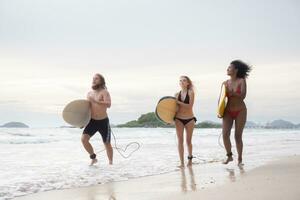 Two women and young man holding surfboards ready to walk into the sea to surf. photo