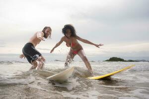 Pareja surf en el playa teniendo divertido y equilibrio en el tabla de surf foto