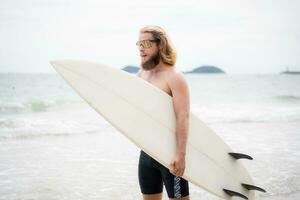 tablista hombre con su tabla de surf en el playa. foto