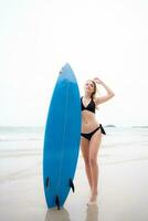 Surfer girl with her surfboard on the beach. photo