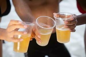 multiétnico grupo de amigos teniendo divertido en el playa, Bebiendo cerveza y teniendo divertido foto