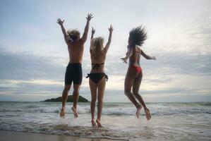 Group of friends having fun on the beach at the sunset time. photo