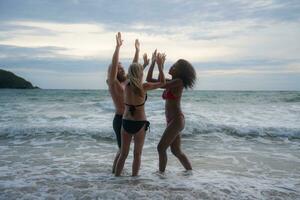 Group of friends having fun on the beach at the sunset time. photo