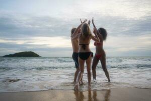 grupo de amigos teniendo divertido en el playa a el puesta de sol tiempo. foto