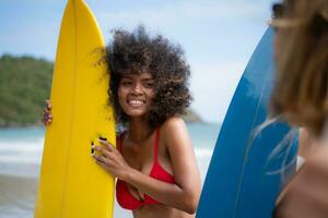 Portrait of smiling young woman in bikini with surfboard at beach photo