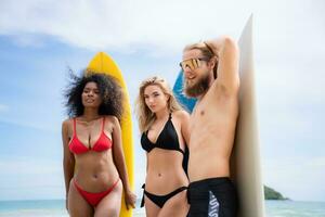 Group of friends in swimsuits posing with surfboards on the beach. photo