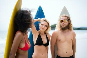 Portrait of smiling young woman in bikini with surfboard at beach photo