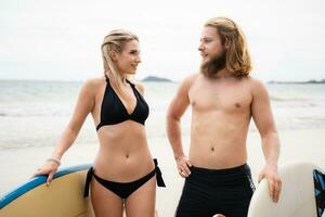 Young couple of surfers with surfboard on the beach photo