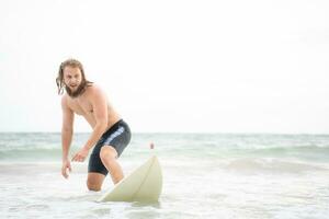 joven hombre surf en el playa teniendo divertido y equilibrio en el tabla de surf foto