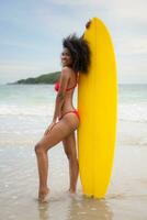 Full length portrait of a young woman with surfboard at the beach photo