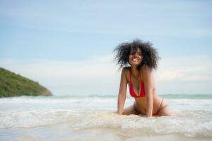 Portrait of a smiling young woman sitting on surfboard at beach photo