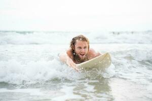 joven hombre surf en el playa teniendo divertido y equilibrio en el tabla de surf foto