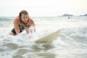 joven hombre surf en el playa teniendo divertido y equilibrio en el tabla de surf foto