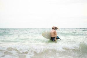 Young man surfing on the beach having fun and balancing on the surfboard photo