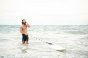 joven hombre surf en el playa teniendo divertido y equilibrio en el tabla de surf foto