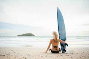 Surfer girl with her surfboard on the beach. photo