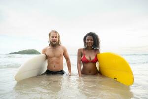 Young couple of surfers with surfboard on the beach photo