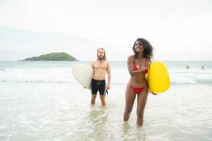 Couple of surfers holding hands and looking at each other on beach photo