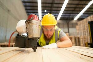 Young workers working in a woodworking factory, Using a nailing machine to assemble wooden pallets photo