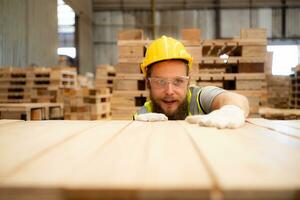 A guy carpenter in a hardhat and glasses inspects a completed work item at a timber industry. photo