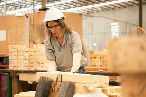 un carpintero trabajos en un carpintería taller. ella recoge el madera ese pasa mediante el madera ángulo amoladora. foto