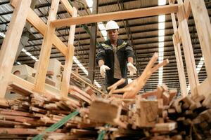 un carpintero trabajos en un de madera fábrica, reunir madera ese tiene pasado mediante el madera cortador dentro pequeño piezas. a ser expedido a ser formado dentro de madera paletas foto