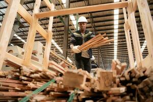 A carpenter works in a wooden factory, Gather wood that has passed through the wood cutter into small pieces. to be sent to be formed into wooden pallets photo