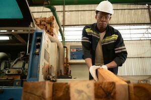 Young man worker work in a woodworking factory, Working with wood sawing and cutting machines to produce wooden sheets for making pallets photo