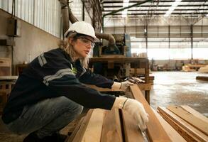 A carpenter works in a carpentry workshop. She collects the wood that passes through the wood angle grinder. photo