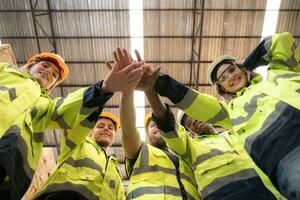 retrato de contento trabajadores dando alto cinco a depósito. esta es un un grande madera fábrica. industrial y industrial trabajadores concepto foto